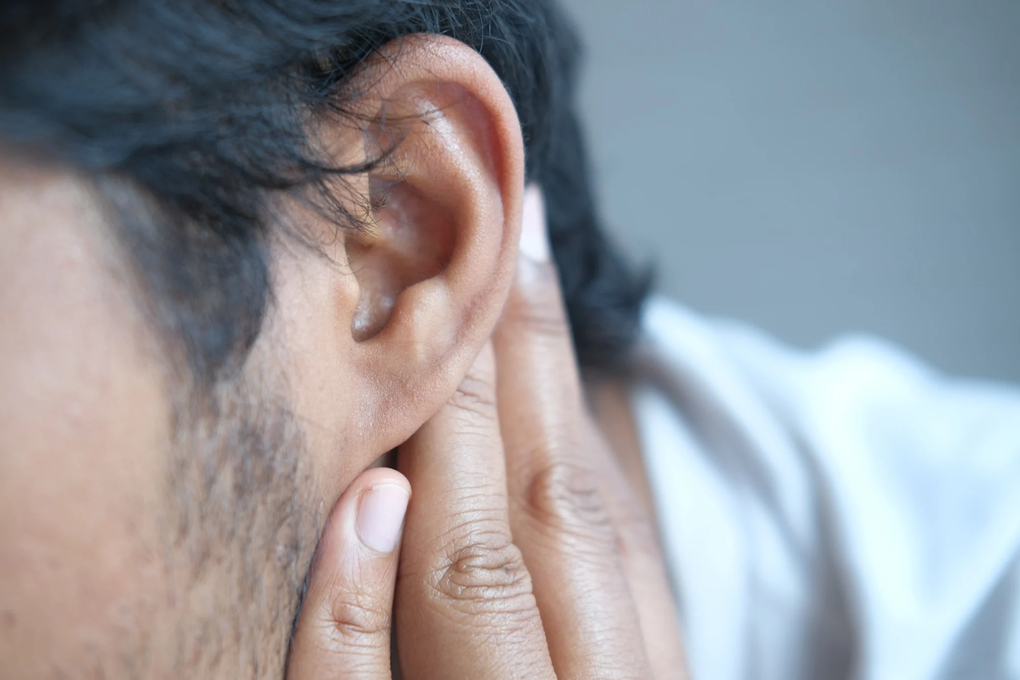 young man having ear pain touching his painful ear ,