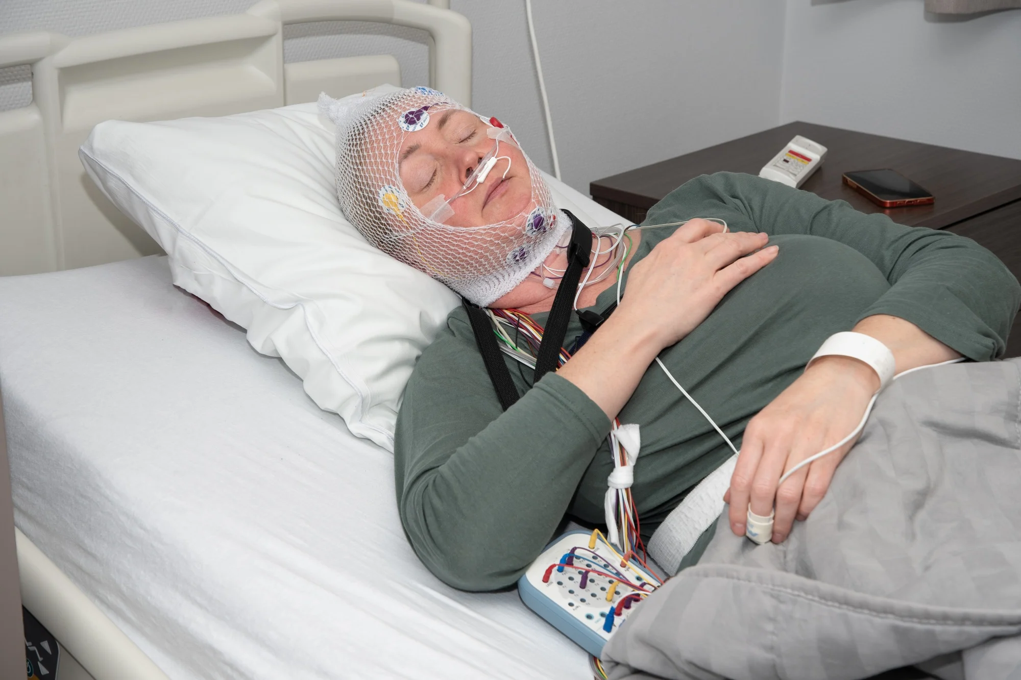 Middle aged woman measuring brain waves, examining polysomnography in sleep lab